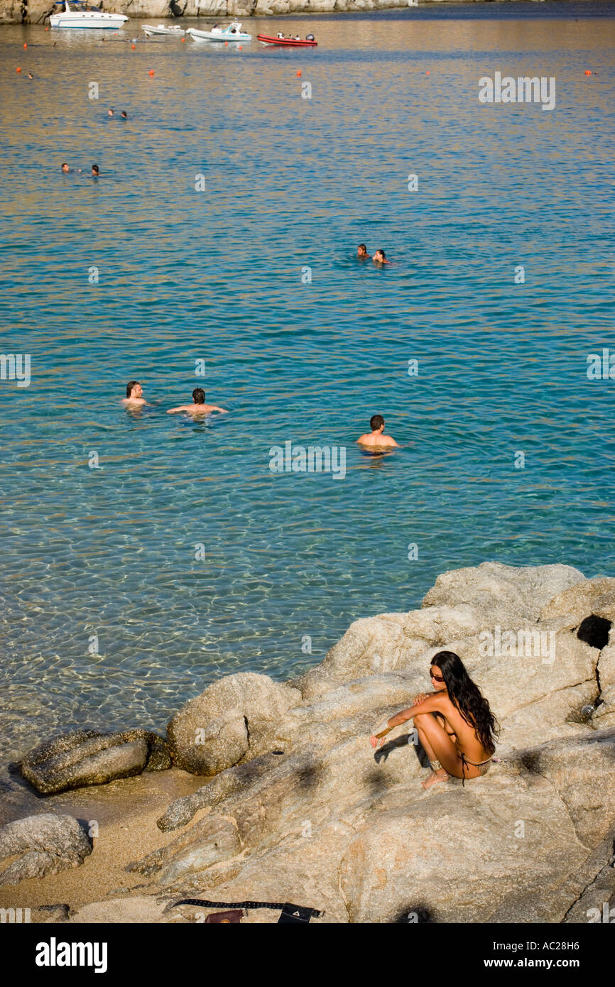 View from a woman sitting on a rock people at Super Paradise Beach knowing as a centrum of gays and nudism Psarou Mykonos Greece Stock Photo