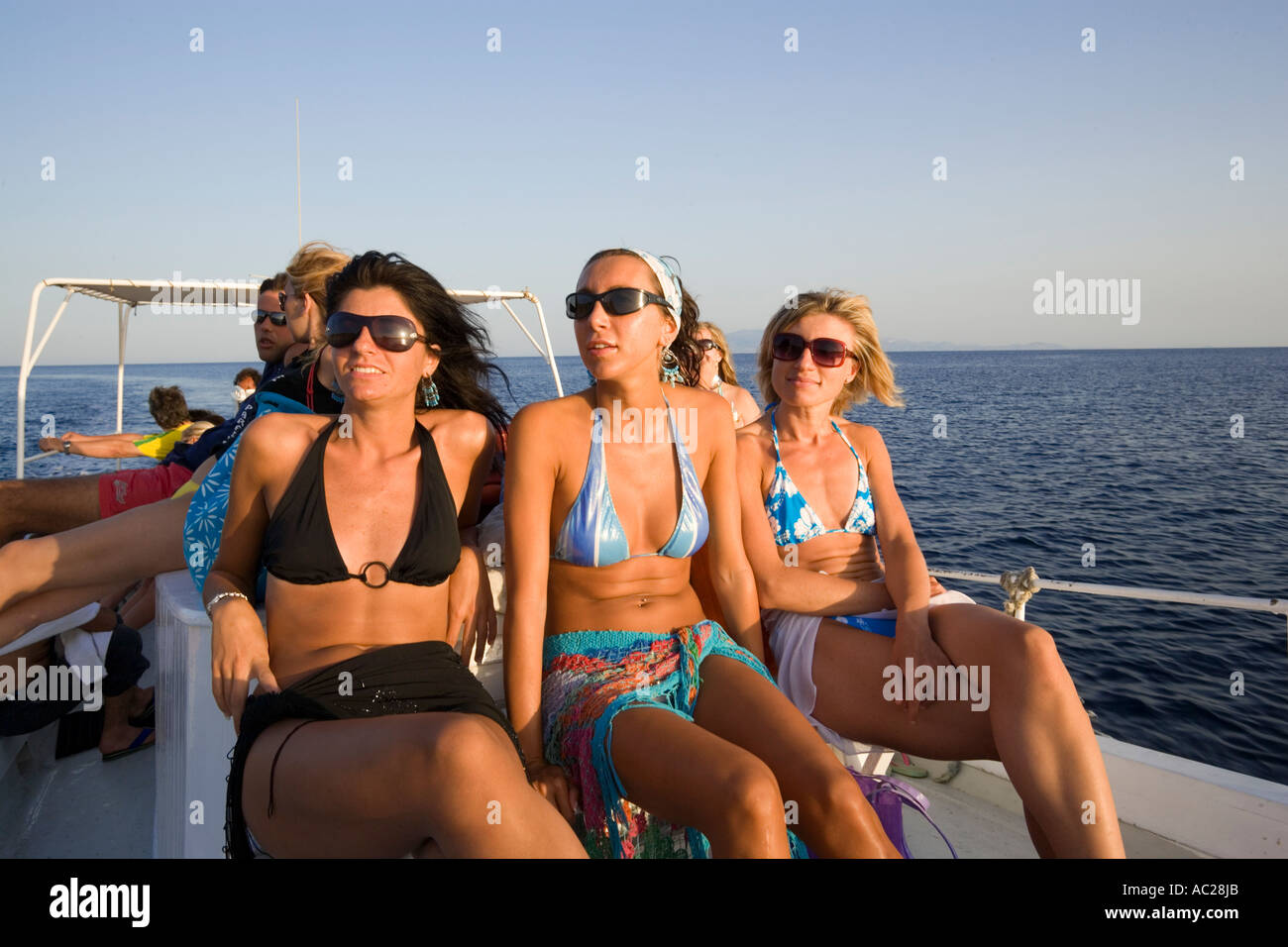 Three women using the boat transport to the Paradise and Super Paradise Beach Psarou Mykonos Greece Stock Photo