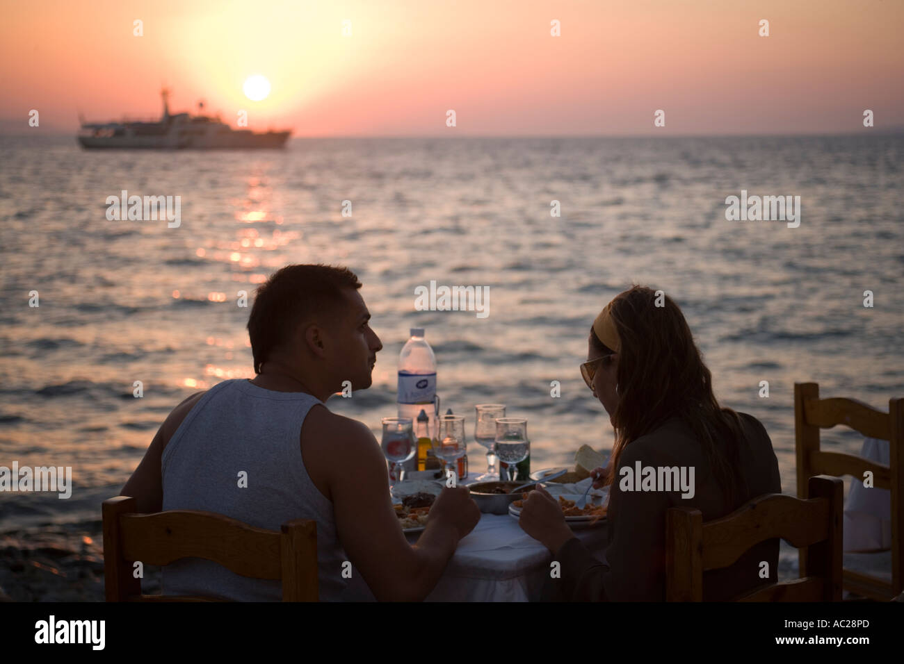Couple eating in a restaurant directly at sea in the dusk Little Venice Mykonos Town Mykonos Greece Stock Photo