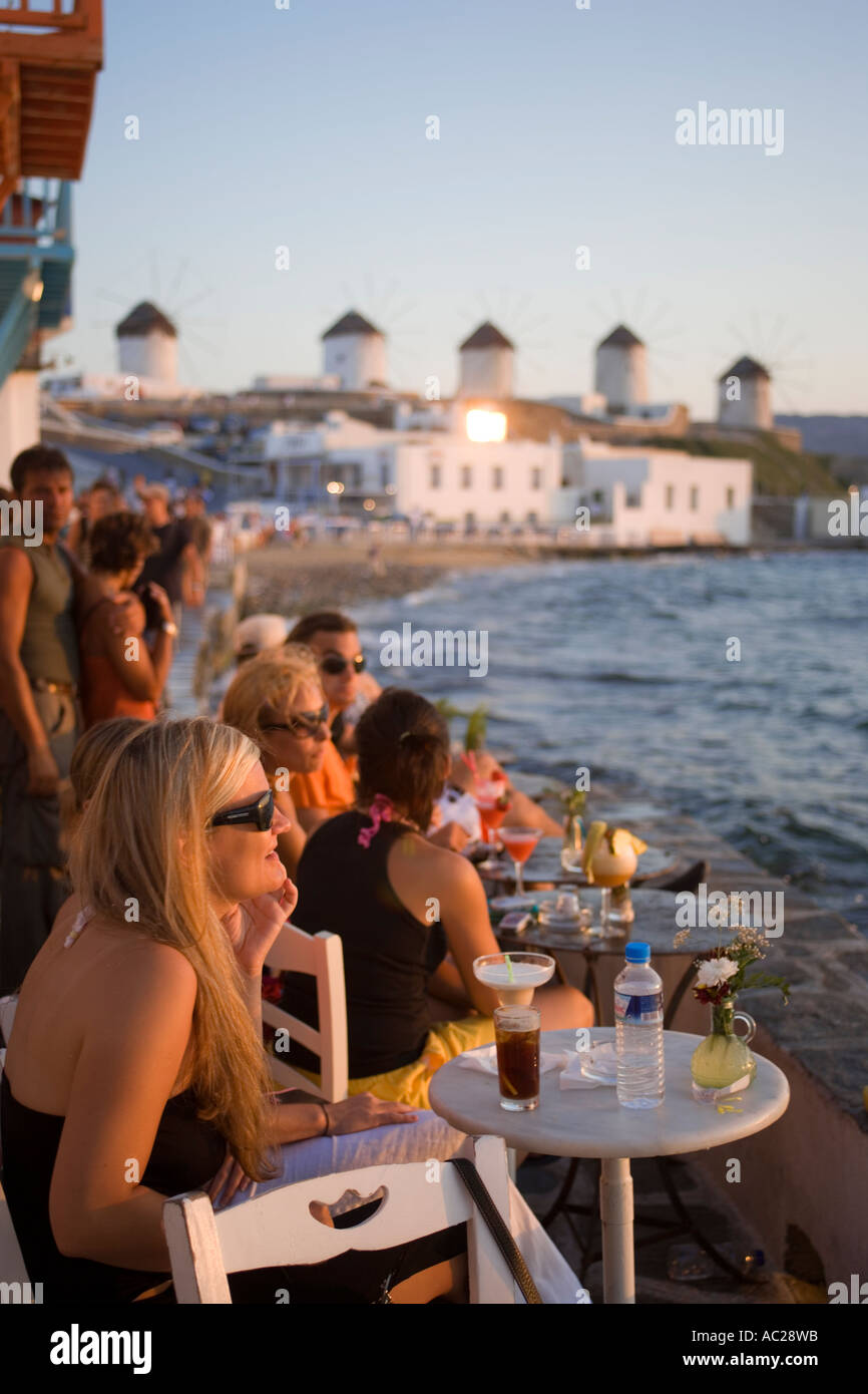 People sitting in a restaurant directly at sea windmills in background Little Venice Mykonos Town Mykonos Greece Stock Photo