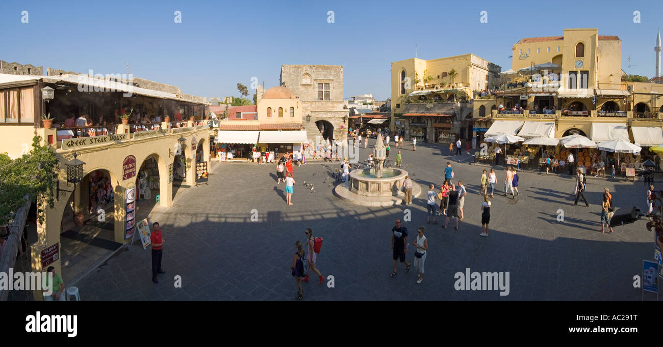 A two picture stitch panoramic image of tourists around the fountain in Ippokratous Square in the centre of Rhodes Old Town. Stock Photo