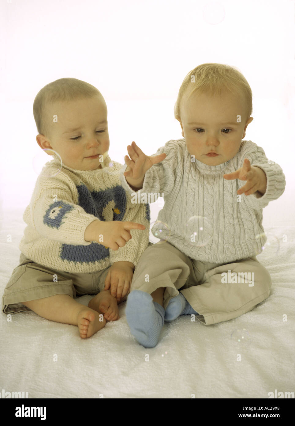 Two baby boys playing together happily with bubbles Stock Photo