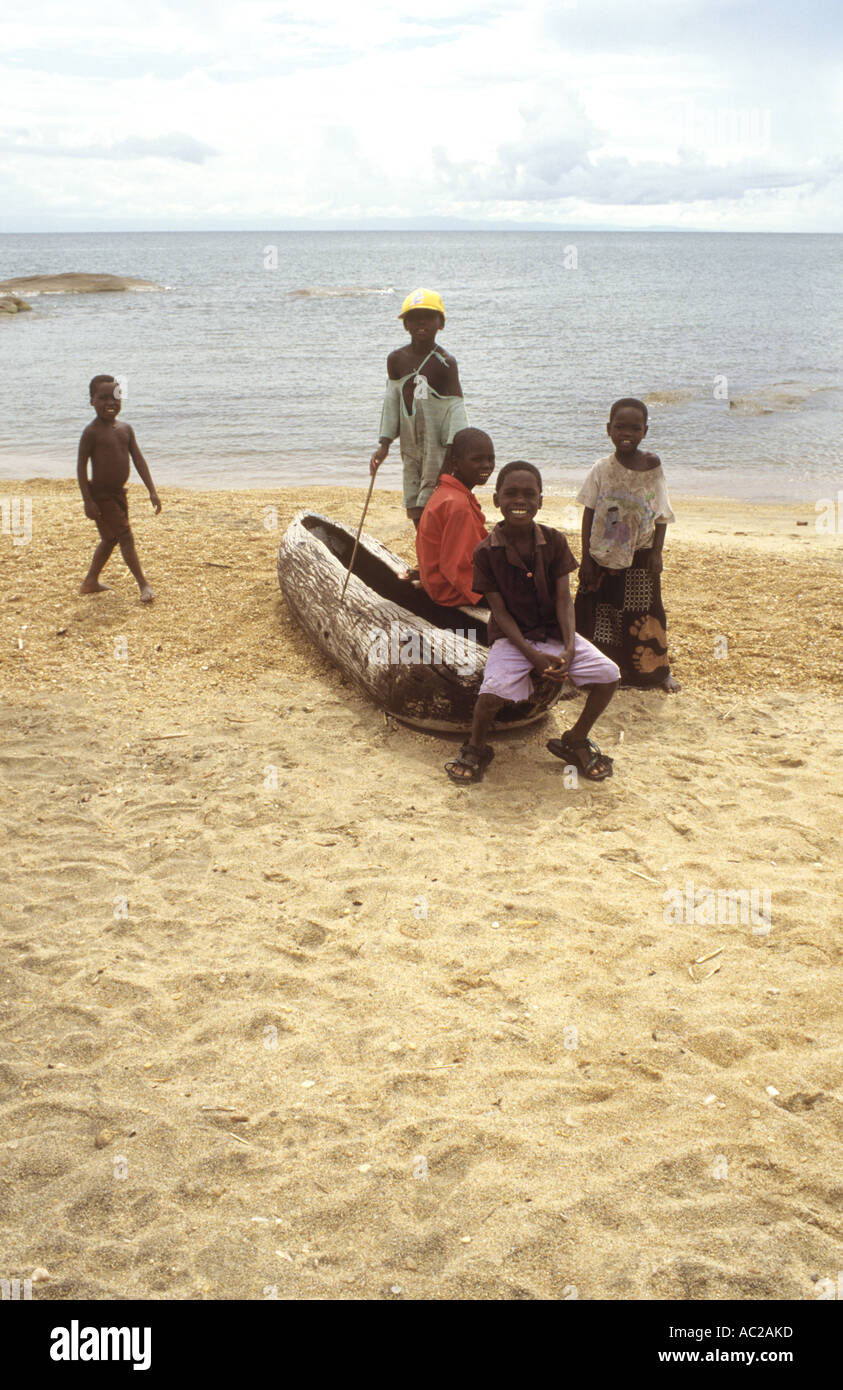 Children pose together next to a dugout canoe beside Lake Malawi, Nkhotakota, Malawi, Africa Stock Photo