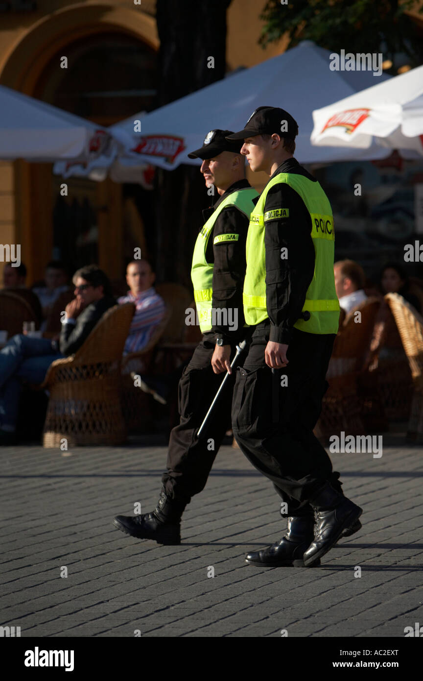 two polish police officers on patrol in front of street cafe in rynek glowny town square krakow Stock Photo