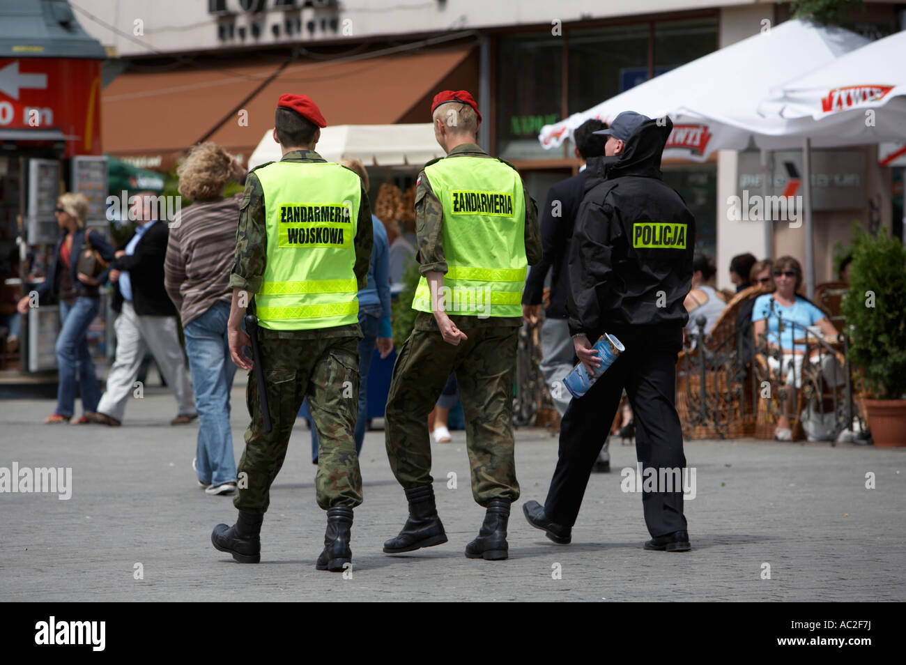 polish military police officers patrol with police officer beside street cafe in rynek glowny town square krakow Stock Photo