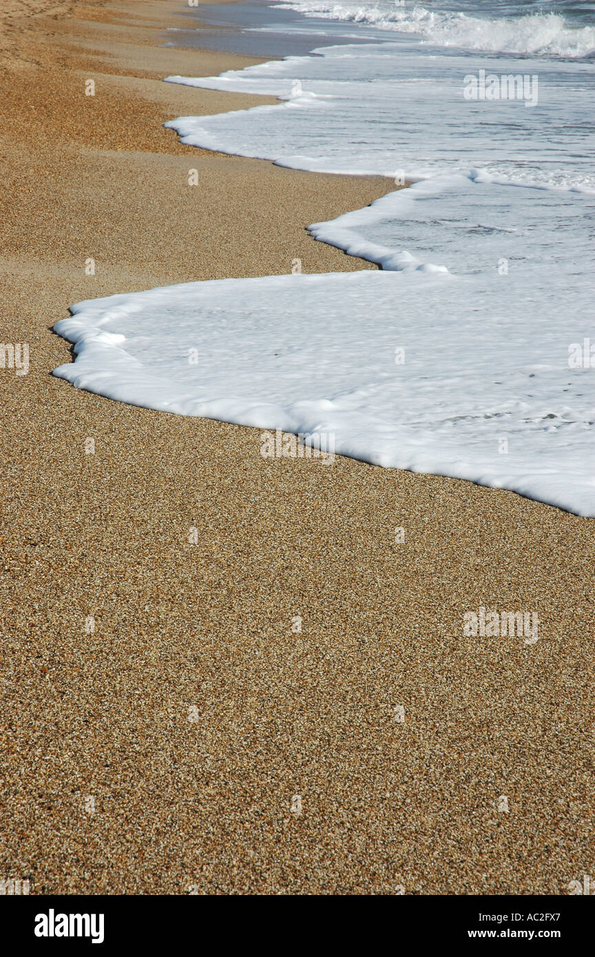 Foam left behind by wave on coarse sand beach Stock Photo