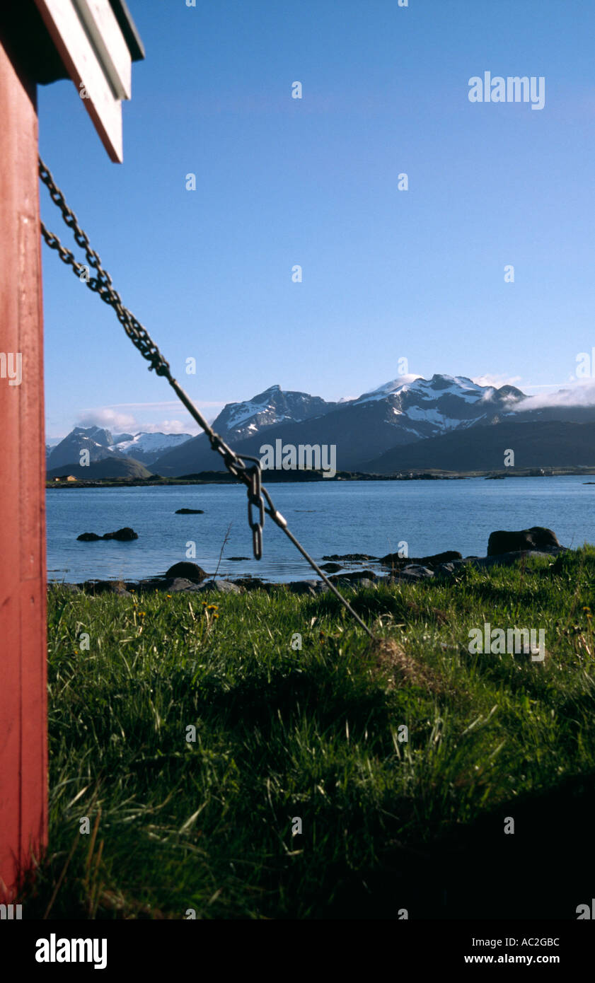 Wood hut chained to the ground to stop it blowing away in the Lofoten Islands Norway mountains in the background Stock Photo