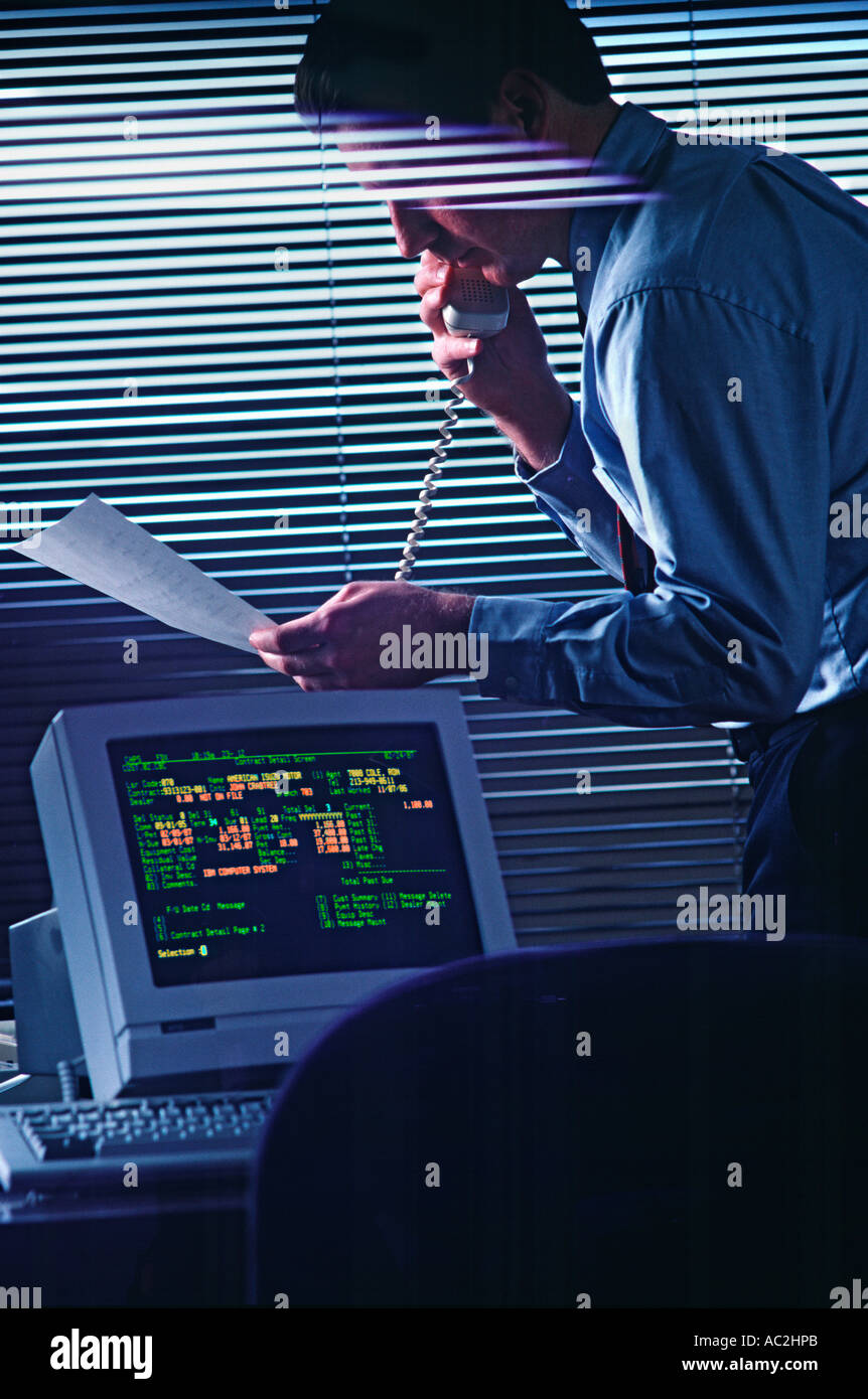 Businessman on phone in office looks over document Stock Photo