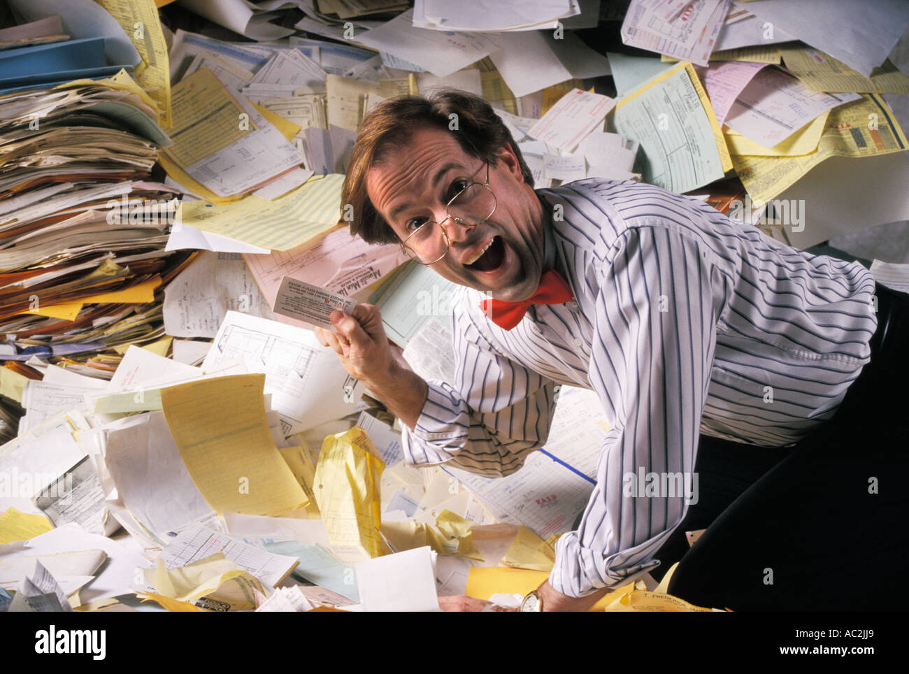 Disorganized businessman finds document in a mess of paperwork Stock