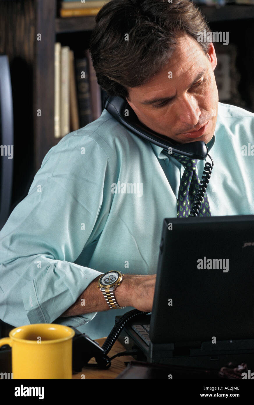 Caucasian businessman talking on phone working on laptop computer Stock Photo
