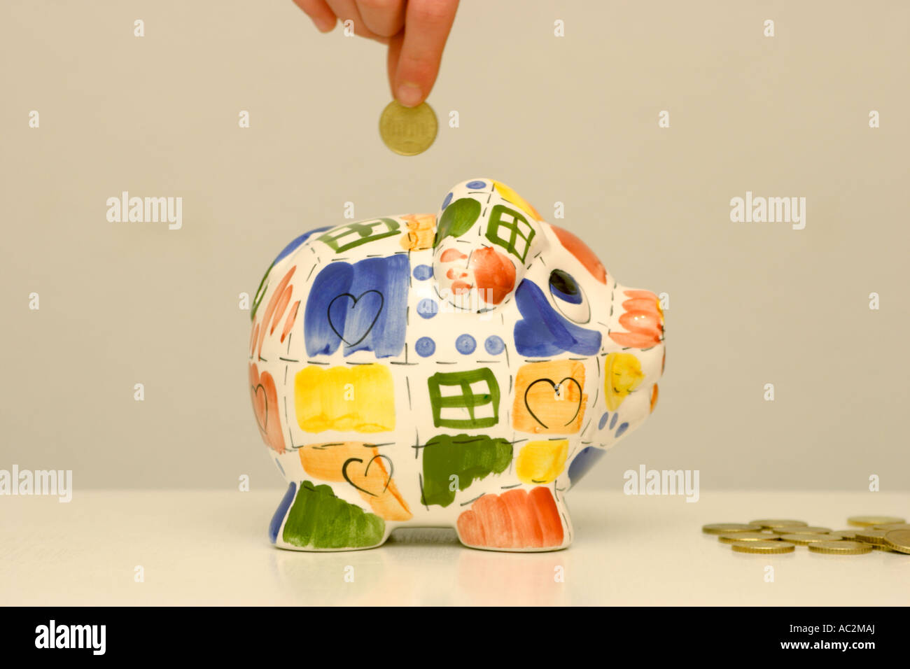 a coin being put into a piggy bank Stock Photo - Alamy