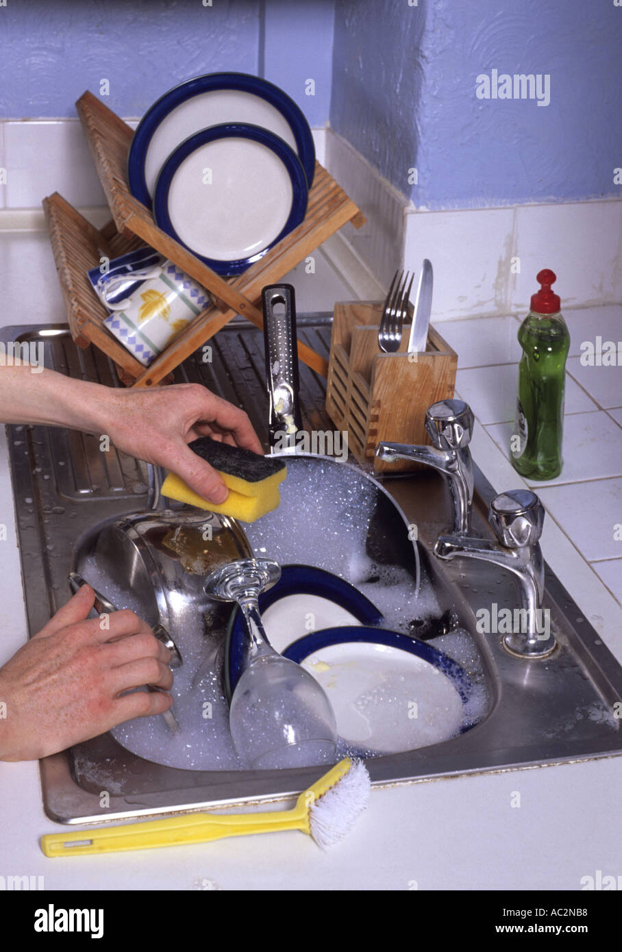 person doing giant mound of dirty washing up left in kitchen sink in house Stock Photo