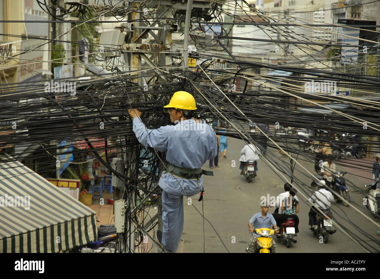 A contractor repairs a jumble of wires in Pham Ngu Lao district in Ho Chi Minh City, Vietnam. Stock Photo