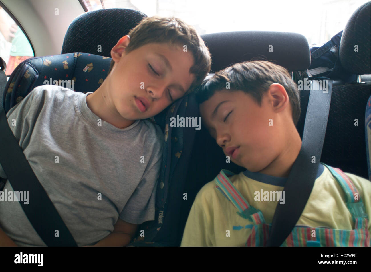 Two young boys sleeping exhausted in the back seat of a car Stock Photo