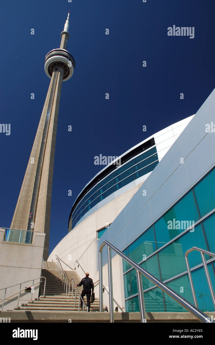 Man walking up stairs at Toronto Convention Centre towards the CN Tower with blue sky Stock Photo
