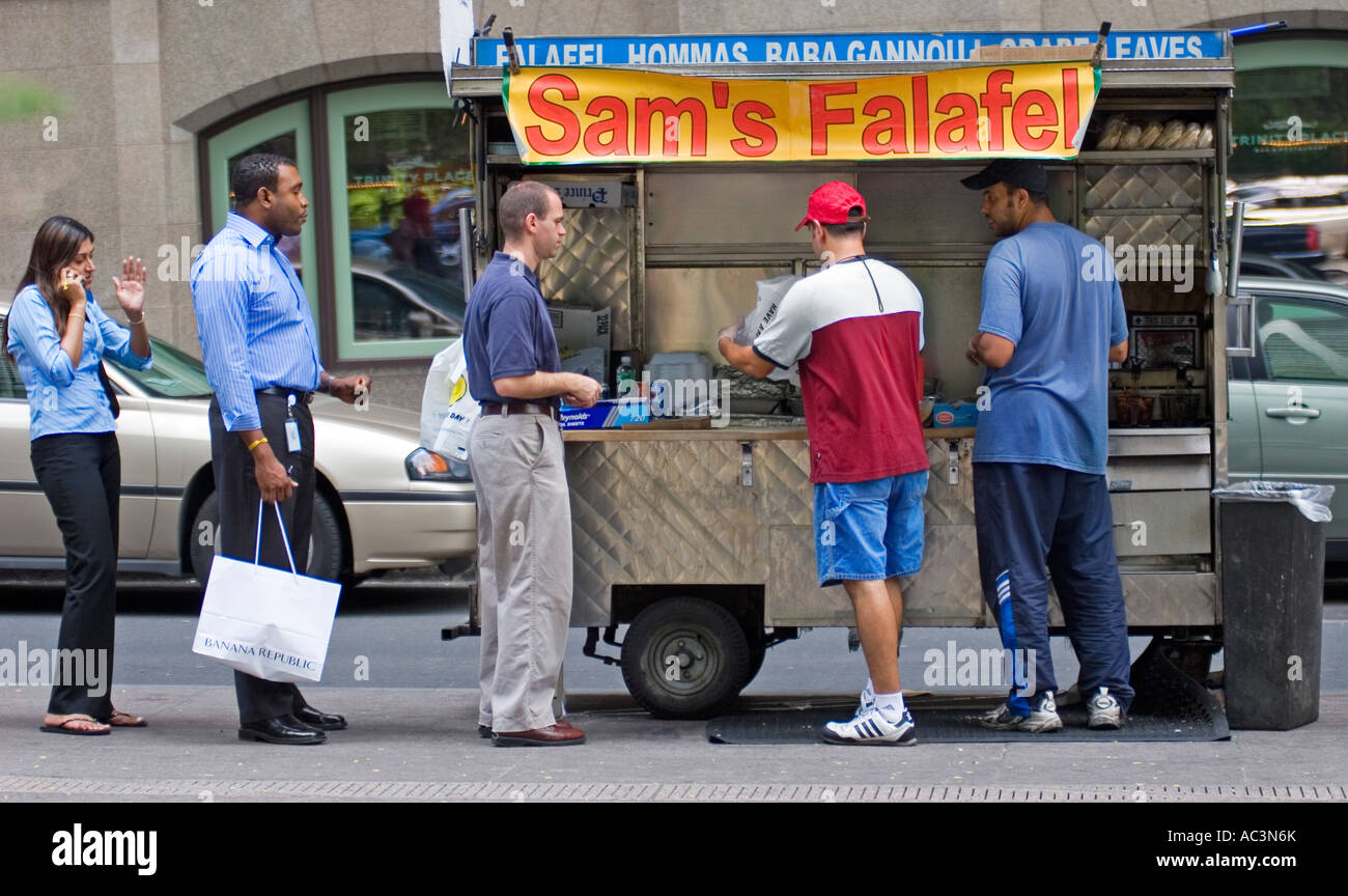 A line of people wait to buy food from a food stand in New York City