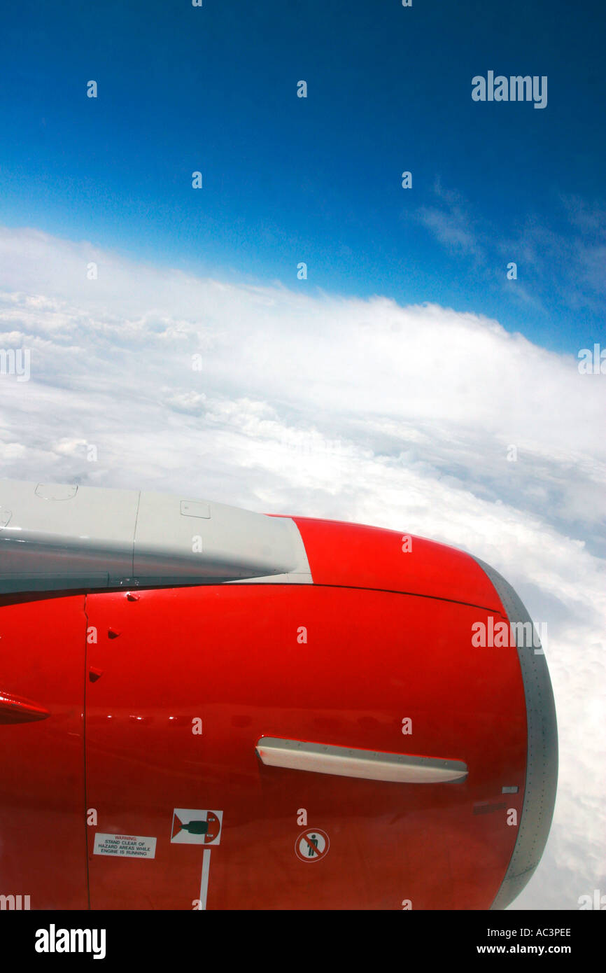 Jet passenger aircraft window view of red engine blue sky and clouds ...