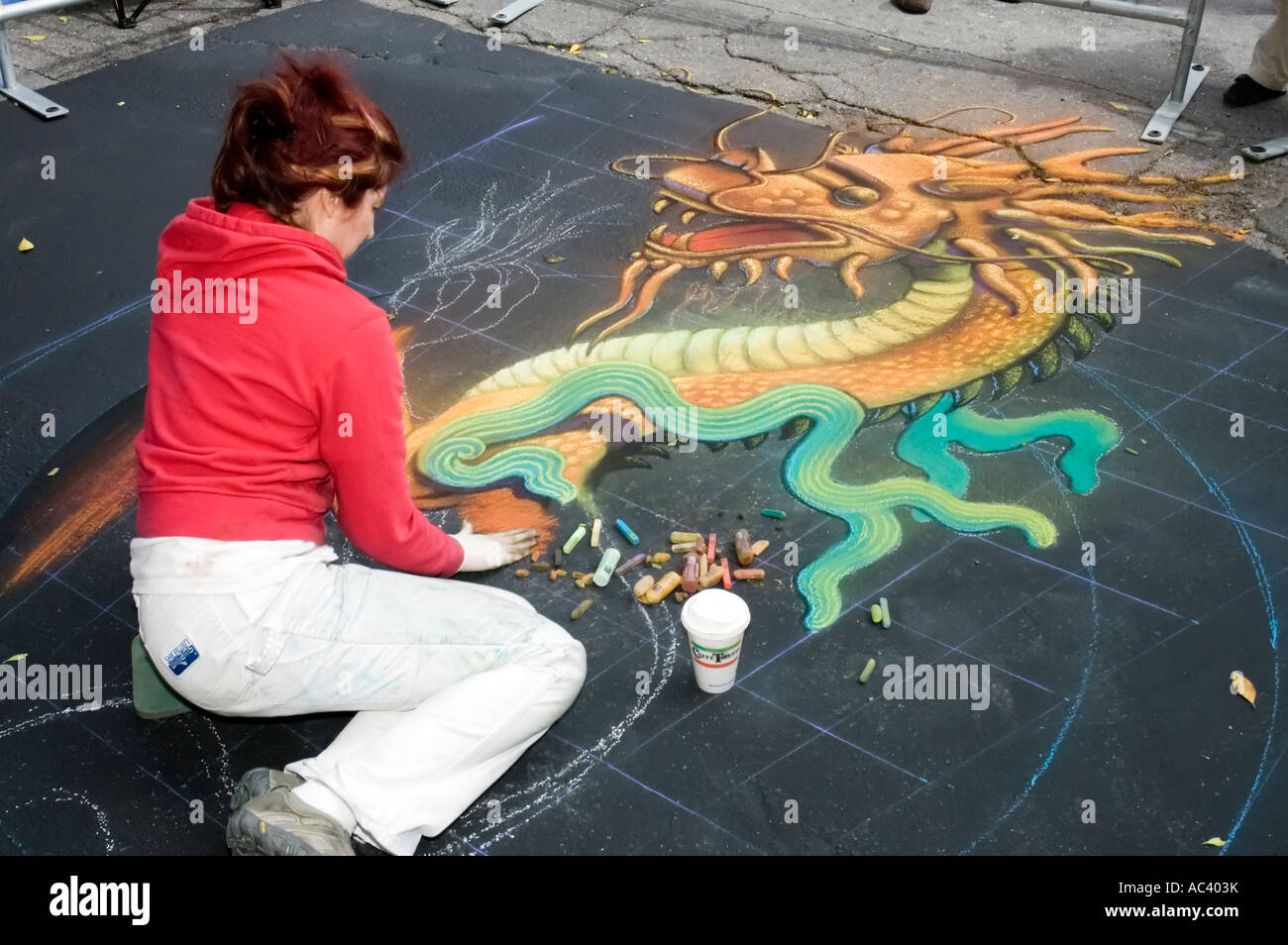 Street artist draws a chinese dragon chalk motif Stock Photo