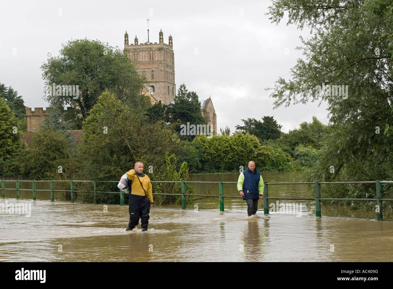 People walking along flooded road opposite Tewkesbury Abbey Gloucestershire UK Stock Photo