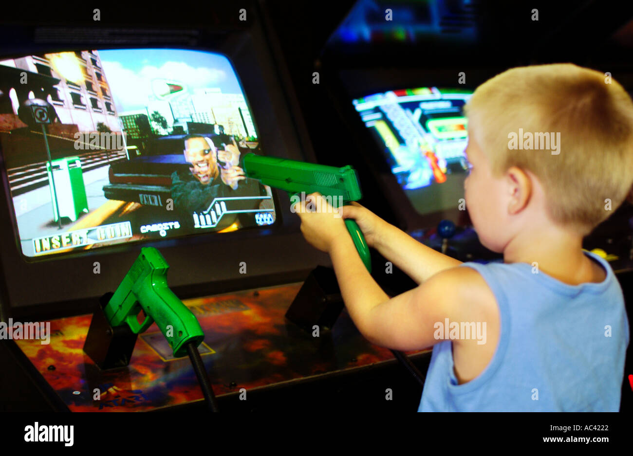 Young boy aiming toy gun at arcade game screen Stock Photo