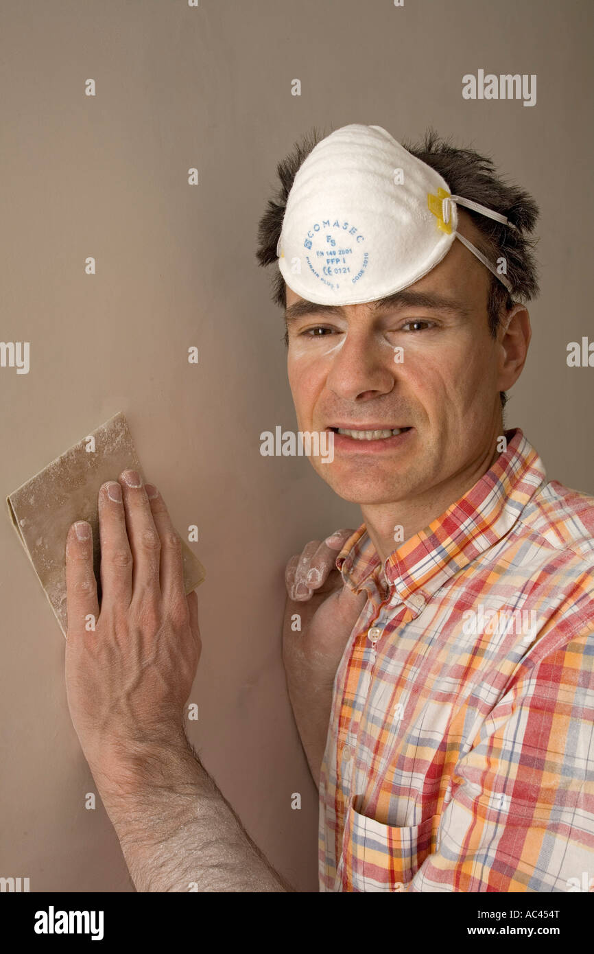 A plasterer sanding down a plastered partition wall (France). Plâtrier ponçant le plâtre d'une cloison (France). Stock Photo