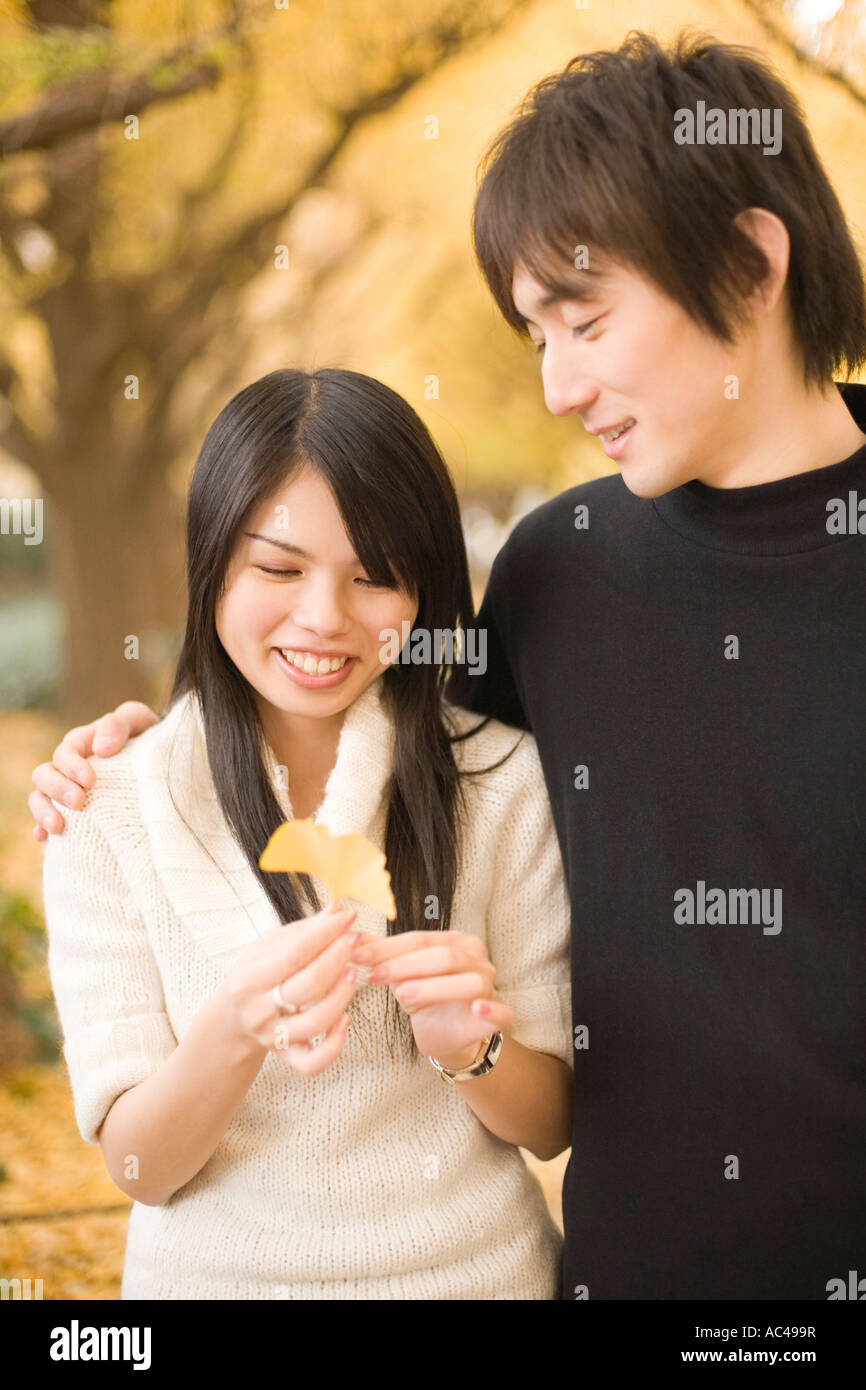 Young couple looking at yellow ginkgo leaf Stock Photo