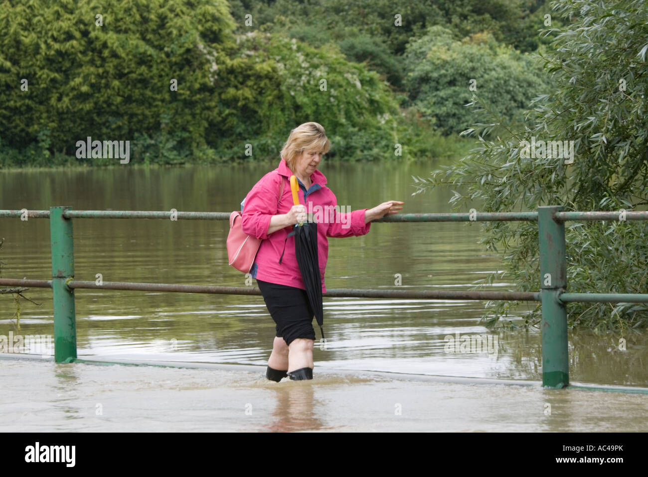 Woman walking along flooded road opposite Tewkesbury Abbey Gloucestershire UK Stock Photo
