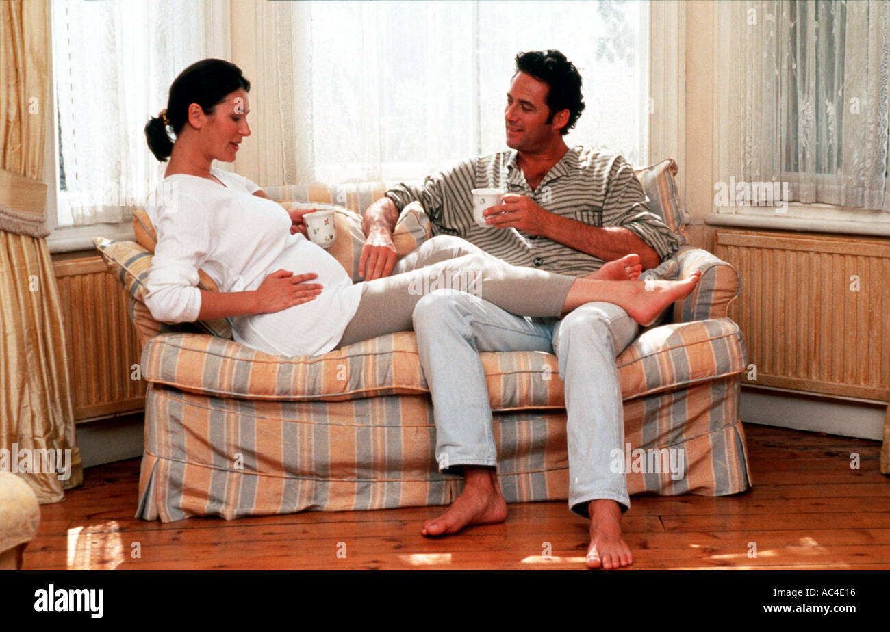 W 18126 26 Model Released Pregnant couple with feet up on sofa drinking Henry Arden RBO Stock Photo