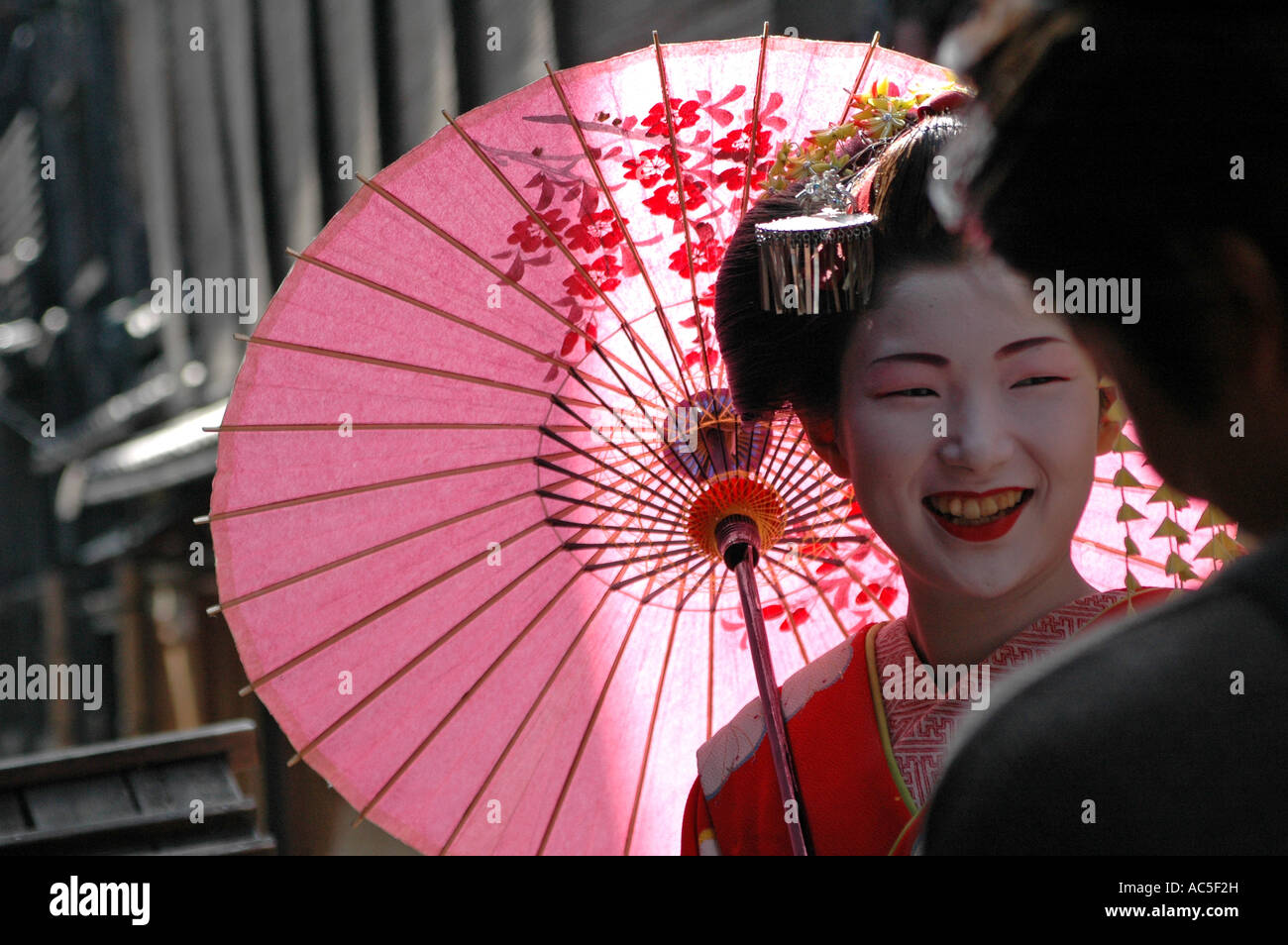 A maiko trainee geisha talks to a man in the Gion district in Kyoto, Japan Stock Photo