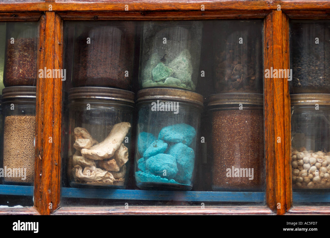 glass containers containing colorful substances, artifacts and herbs on display in shop window