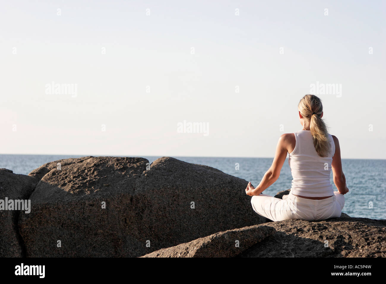 Thailand Woman meditating on rock rear view Stock Photo - Alamy