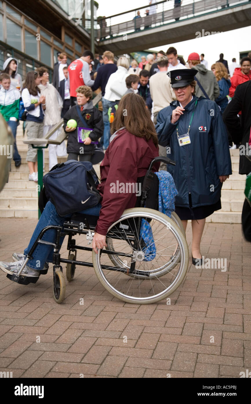 security officer assists a woman in a wheelchair who is unable to use stairs at Wimbledon tennis Championship UK Stock Photo