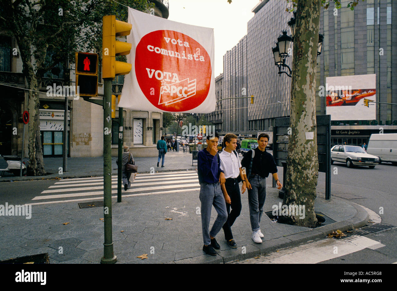 THREE YOUTHS WALKING BENEATH STREET BANNER DECLARING VOTA COMMUNISTA VOTA PCC BARCELONA 10 13 1989 Stock Photo