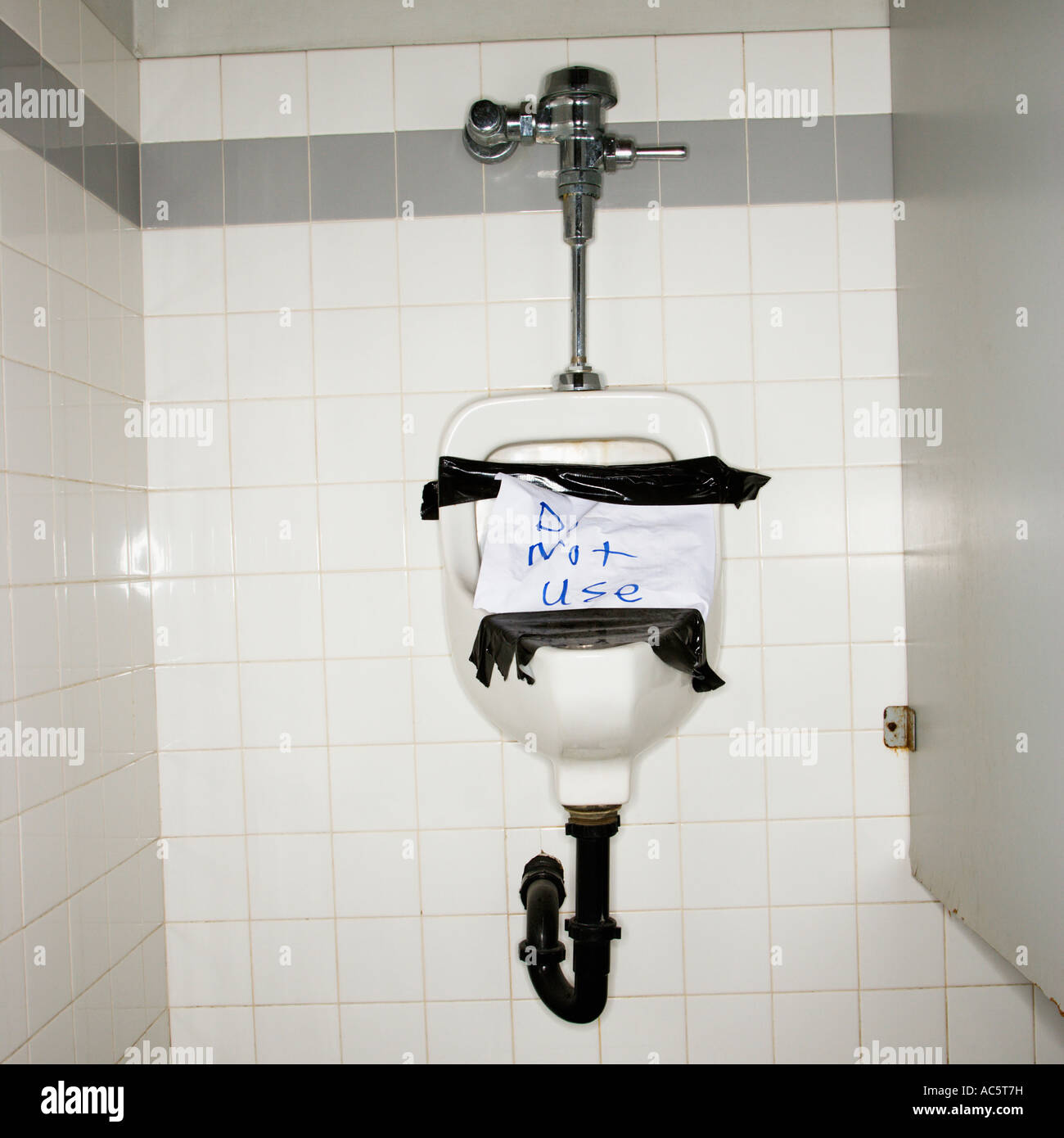 Urinal in men s bathroom with an out of order sign taped on it Stock