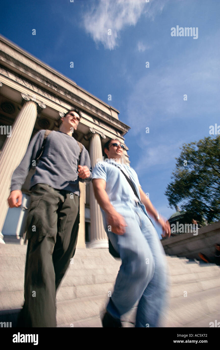 Two young adult students walking down steps with columns in background Two young adult students walking down steps columns Stock Photo