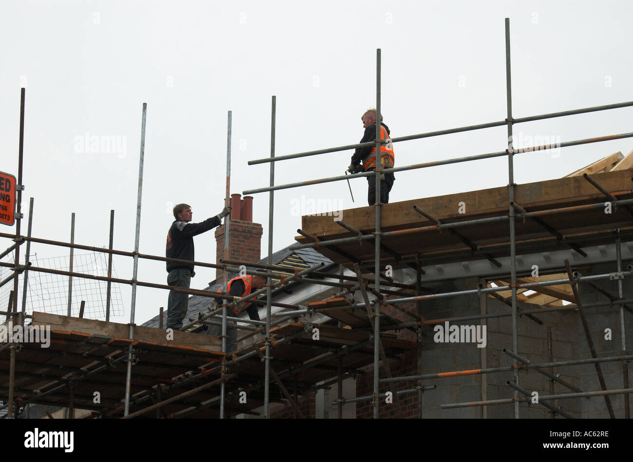 Construction workers tiling a roof on a block of flats in Filey North