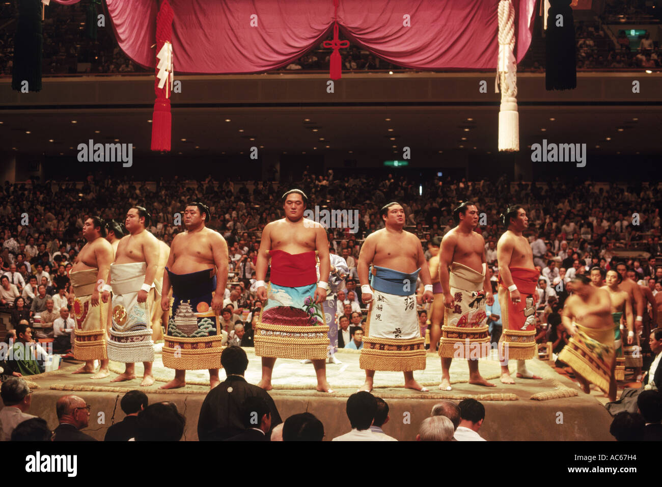 Pre fight sumo wrestling ceremony of  competitors parading around ring or dohyo in traditional costume Stock Photo