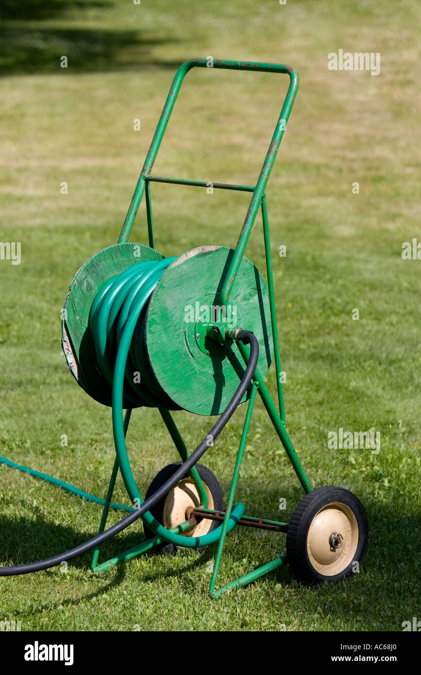 Green wheeled hose reel packed with green plastic hose , Finland Stock