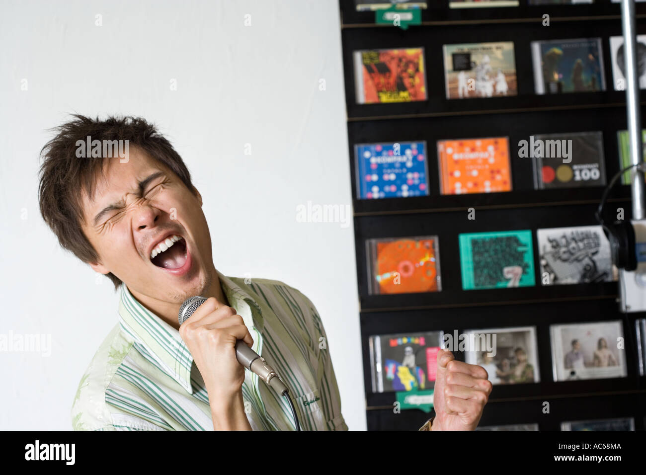 young man sings on microphone in record store Stock Photo - Alamy