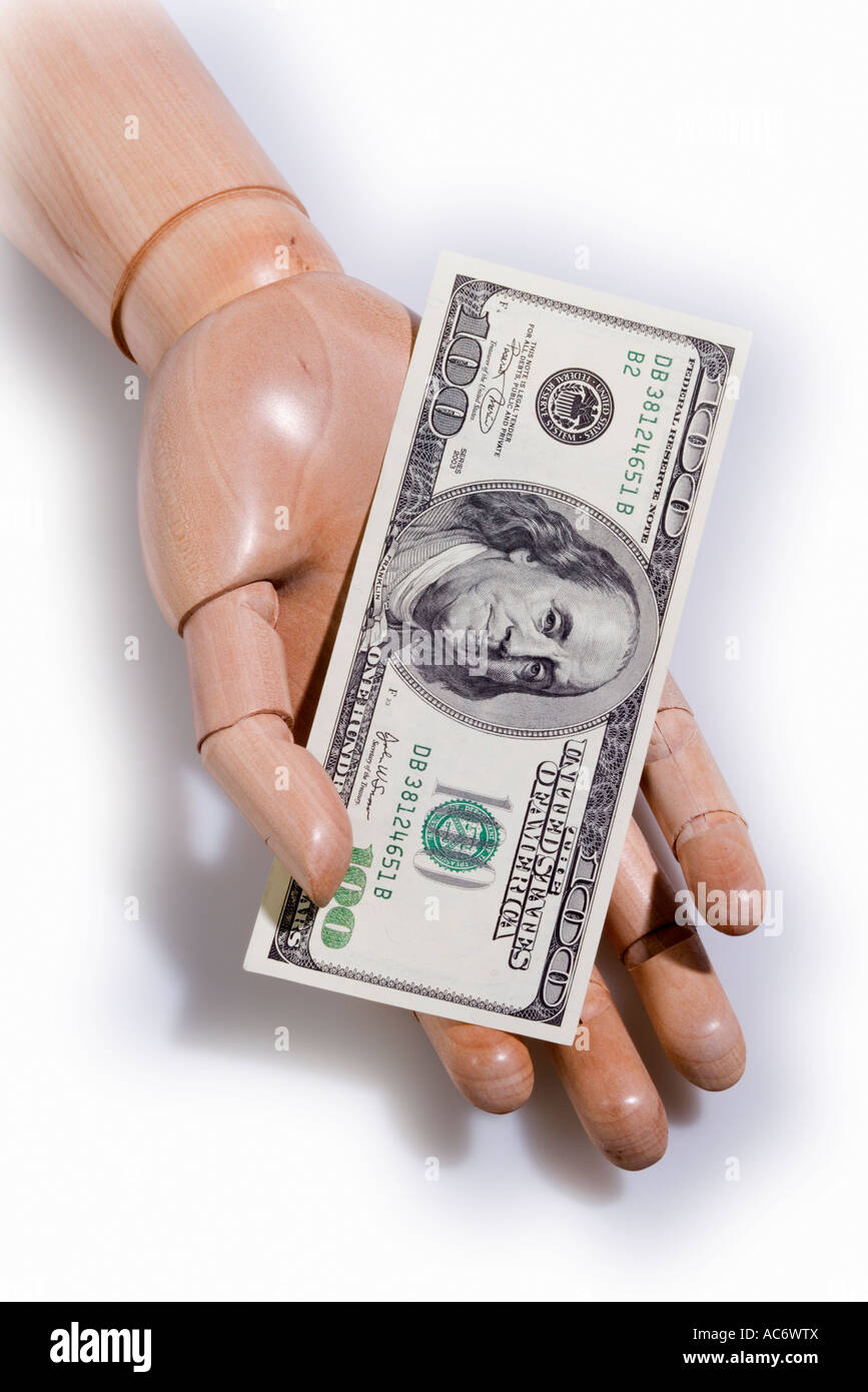 Wooden articulated mannequin hand holding 100 dollar bill Stock Photo