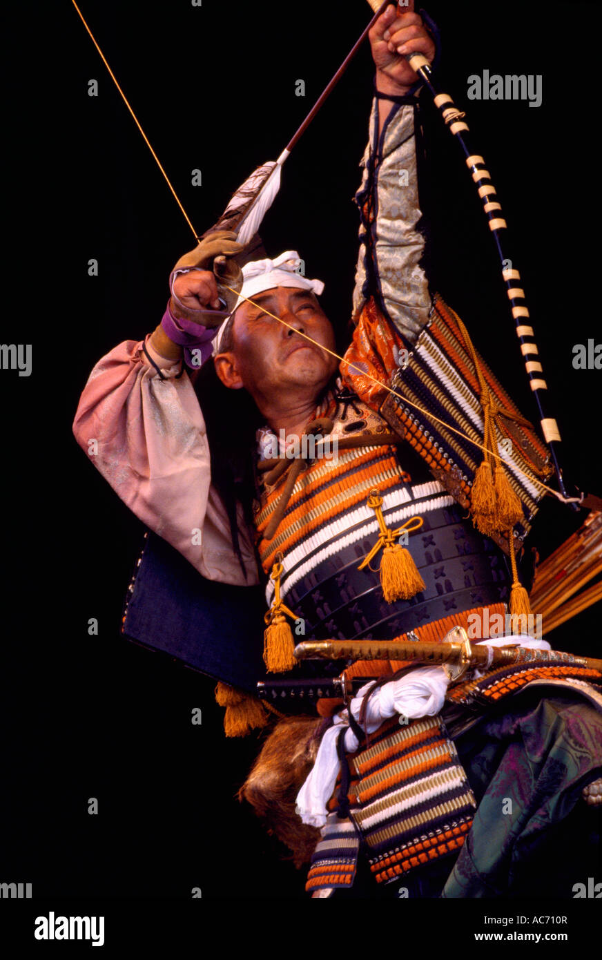 A Japanese Warrior Actor shooting Bow and Arrow in Archery Ritual Stage Performance and wearing Traditional Costume from Japan Stock Photo