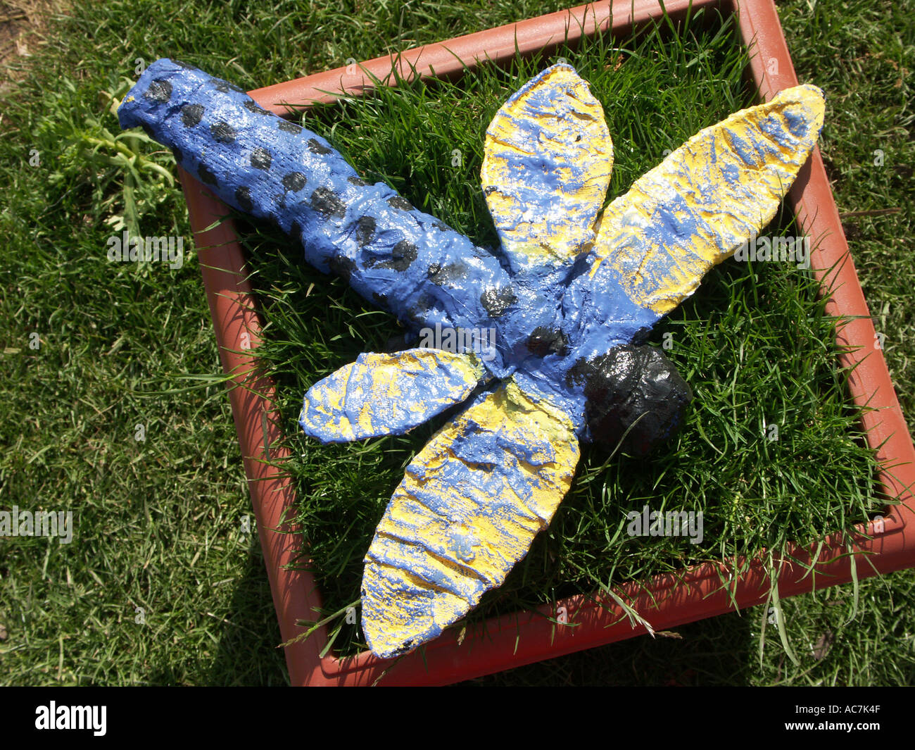 blue paper mache dragonfly in the children’s garden at the spring