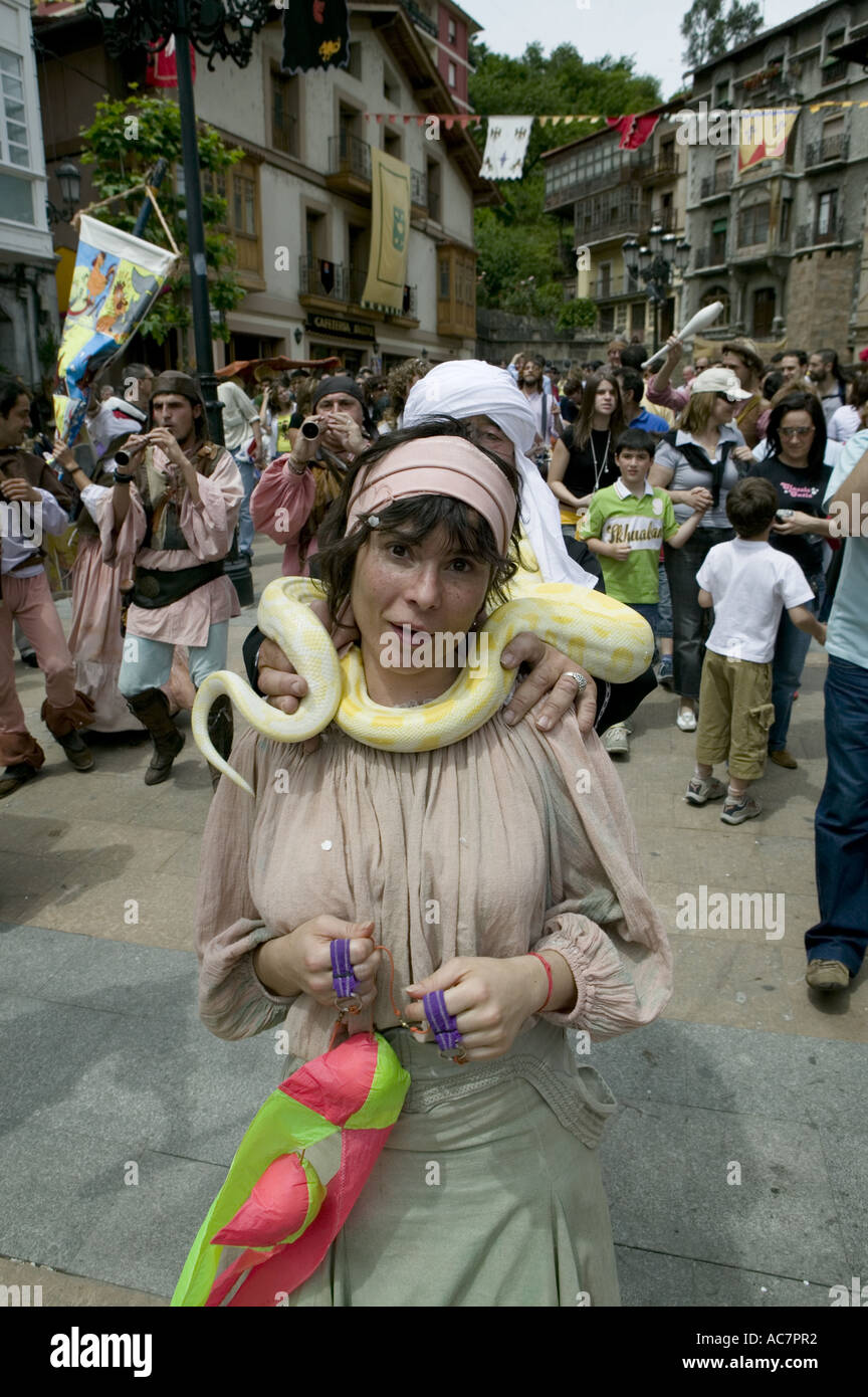 Large yellow snake around the neck of a female dancer during medieval market, Balmaseda, Basque Country Stock Photo