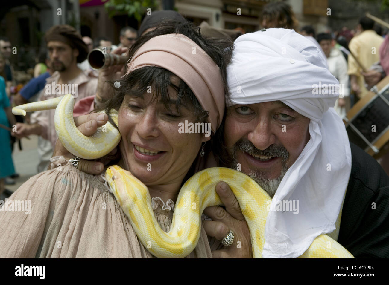 Man wearing turban holds a largesnake around the neck of a female dancer, Balmaseda, Basque Country Stock Photo