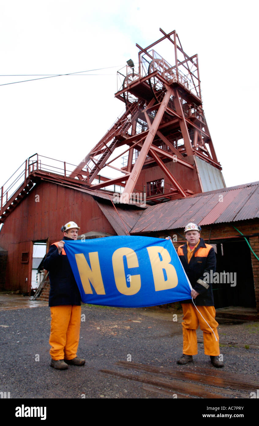Guides, former miners,  with NCB 'National Coal Board' flag at the Big Pit National Coal Museum Blaenavon South Wales UK Stock Photo