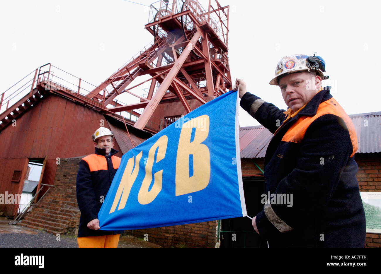 Guides, former miners,  with NCB 'National Coal Board' flag at the Big Pit National Coal Museum Blaenavon South Wales UK Stock Photo