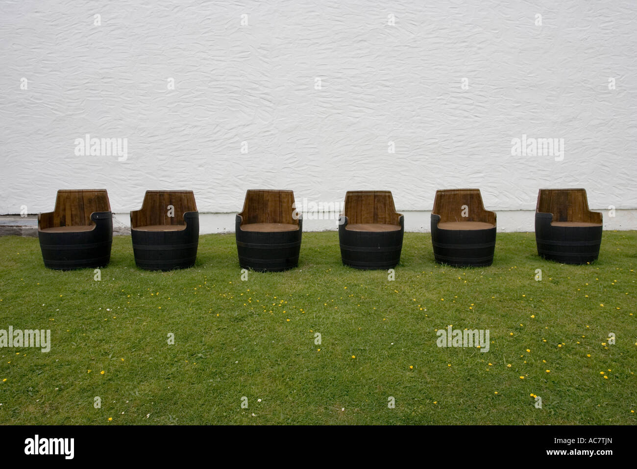 Row six empty barrels made into seats Ardbeg whisky distillery Isle of Islay Scotland UK Stock Photo