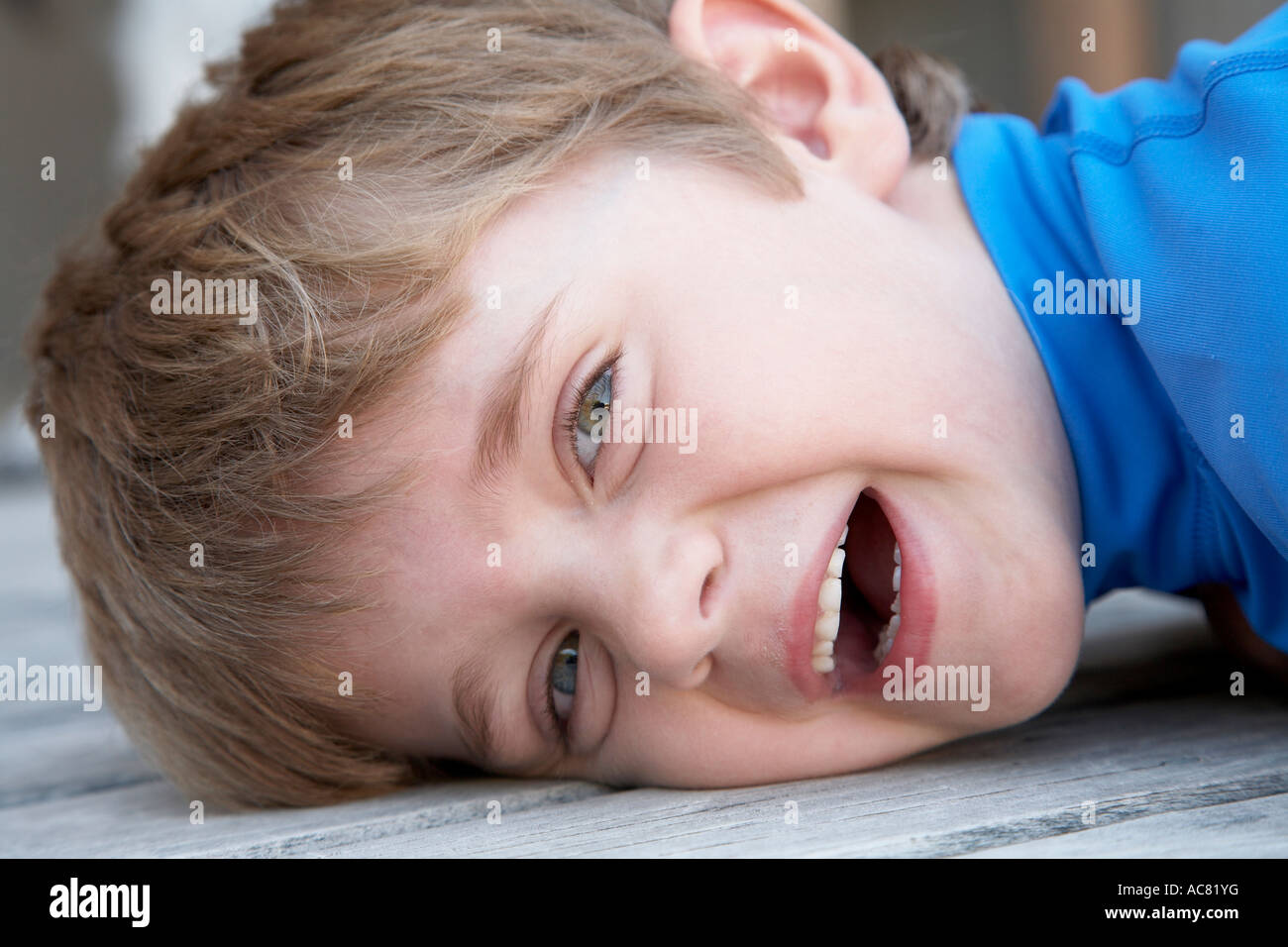 boy 7 laying on deck smiling Stock Photo