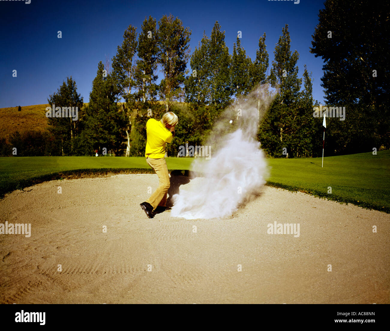 Golfer explodes his ball from the sand in a bunker Stock Photo