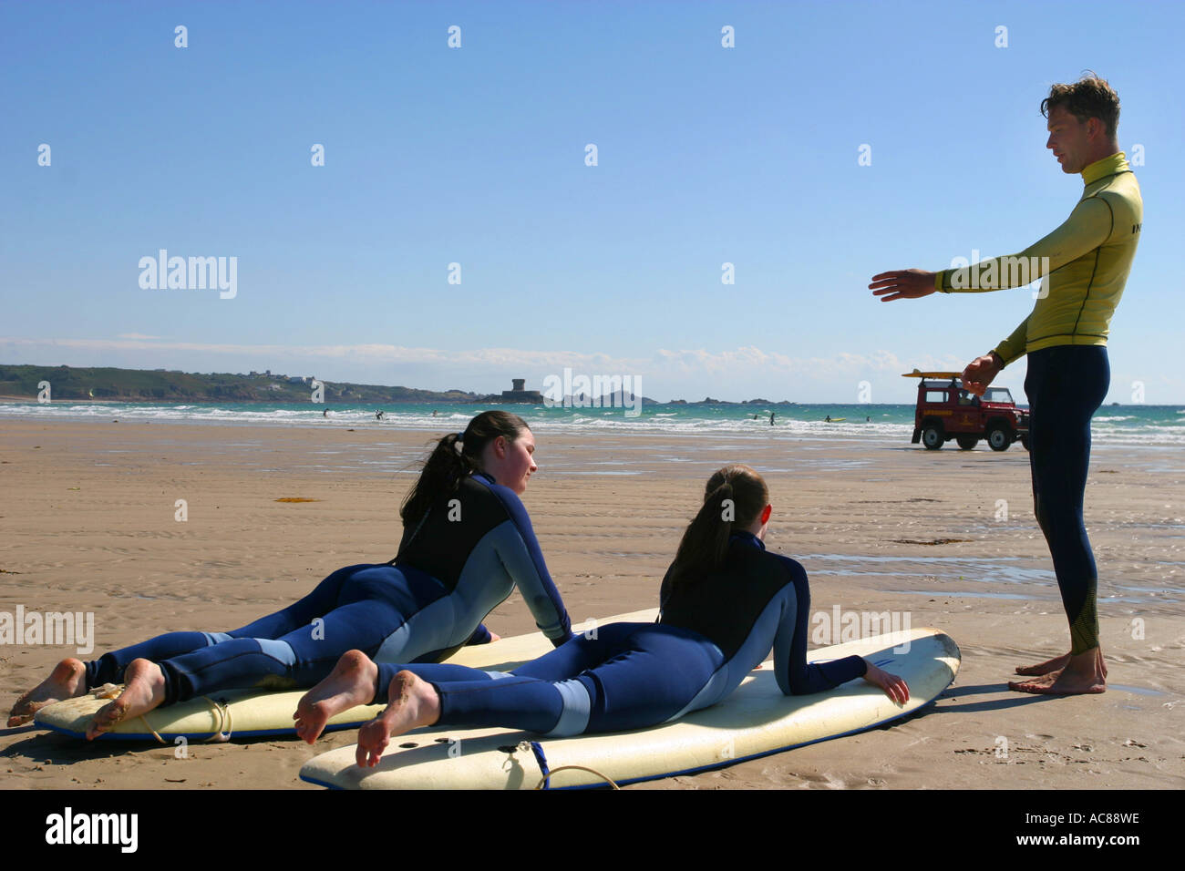 Two young teenage girls first surfing lesson on St Ouen's Beach Jersey